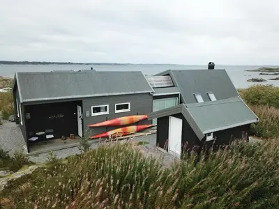 a house with kayaks on the side of it at Kuvågen 23 in Vågenes