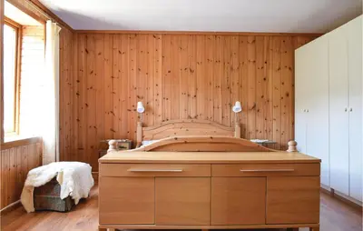 a bedroom with a bed with a wooden wall at 4 Bedroom Beautiful Home In Steinstø in Steinstø