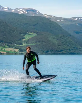 a man on a surfboard in the water at Vågåvatnet Feriesenter in Vågåmo