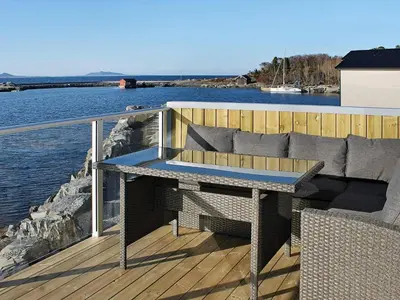 a deck with a bench on the side of the water at 10 person holiday home in Brattvåg in Brattvåg