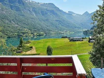 a view of a lake and mountains with a red bench at 8 person holiday home in olden in Olden