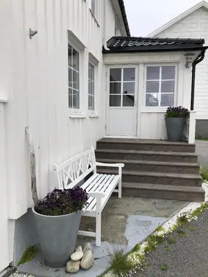 a white bench sitting in front of a house at Olsens Pensjonat in Veiholmen