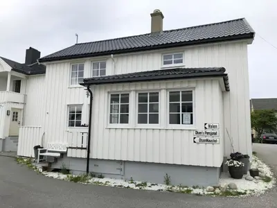 a white house with a bench in front of it at Olsens Pensjonat in Veiholmen