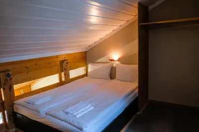 a small room with a bed with white sheets at Hemsetunet Apartments in Hemsedal