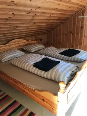two beds in a room with wooden walls at Charming Lakeside House with sauna in Lillehammer