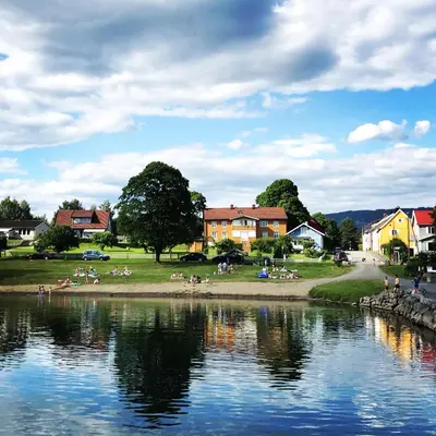 a group of people sitting on the shore of a lake at Charming Lakeside House with sauna in Lillehammer