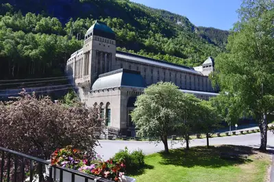 a large building with a mountain in the background at Rjukan Gjestehus in Rjukan