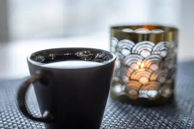 a black cup of coffee sitting on a table at Skaimsberg Holiday Apartments in Aurland