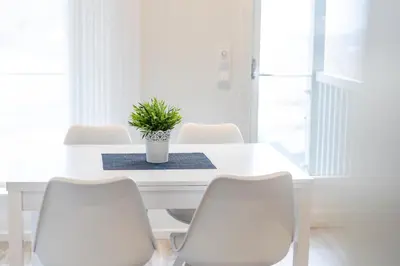 a white dining room table with white chairs and a potted plant at Skaimsberg Holiday Apartments in Aurland