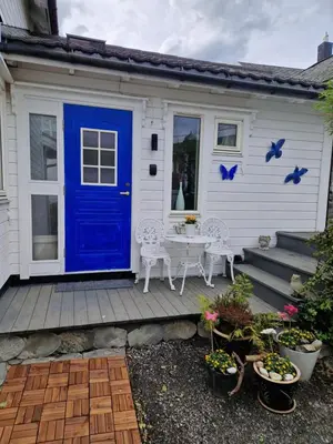 a blue door on a white house with a table and chairs at Huset på hauen in Volda