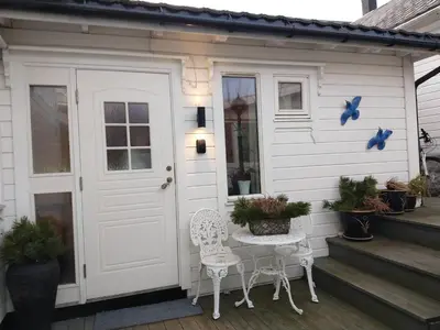 a white house with two chairs and a door at Huset på hauen in Volda