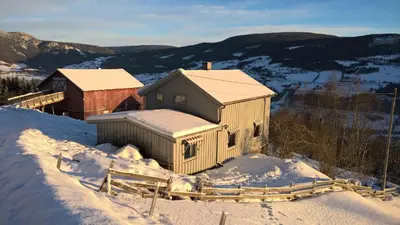 a house in the snow with a barn in the background at Lille Randklev Gæstehus in Ringebu