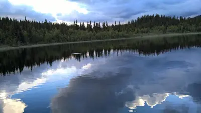 a lake with the reflection of the clouds in the water at Lille Randklev Gæstehus in Ringebu