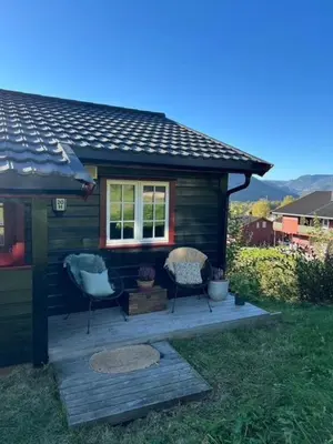 a small cabin with two chairs on a deck at Sørlia hytte in Hafjell