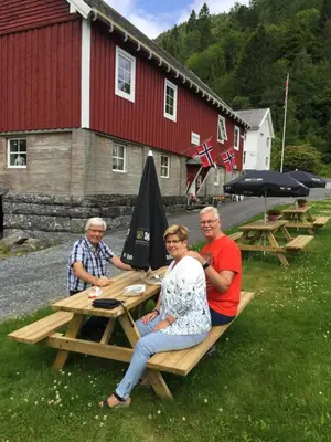 a group of people sitting at a picnic table at Josygaard in Austefjorden