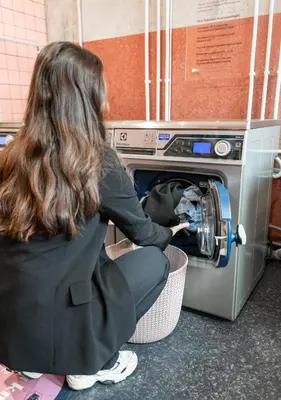 a woman is loading a clothes into a washing machine at Citybox Bergen Danmarksplass in Bergen