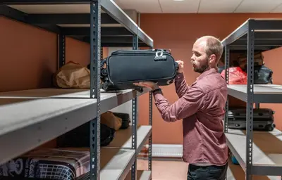 a man is holding a suitcase on a shelf at Citybox Bergen Danmarksplass in Bergen