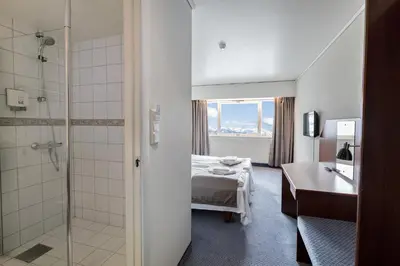 a room with a bed and a bathroom with a shower at Dreges Hotell - by Classic Norway Hotels in Stranda