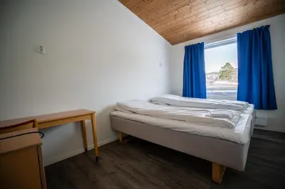 a bedroom with a bed and a window with blue curtains at Dombåstun Motel in Dombås