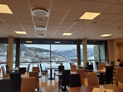 a restaurant with tables and chairs and a large window at Dombåstun Motel in Dombås