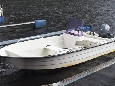 a white boat is docked at a dock at Seaside Serenity in Leirvik-By Traum in Bø