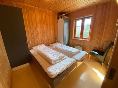 a room with two beds and a chair in it at Hafjell Grenda lejligheder og hytter in Hafjell