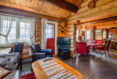 a living room in a log cabin with a television at Ideal For Families 6 Bedrooms, Hot Tub And Sauna in Beitostøl