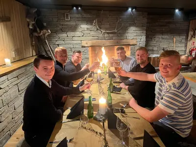 a group of men sitting around a table with wine glasses at Klingenberg Hotel - Årdal in Årdalstangen
