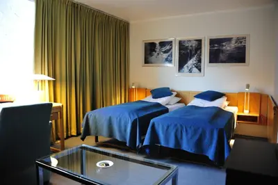 a hotel room with two beds with blue sheets at Klingenberg Hotel - Årdal in Årdalstangen