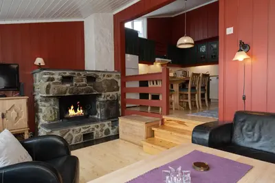 a living room with a stone fireplace and a table at Bitigrenda B in Beitostøl