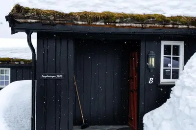 a black shed with a grass roof with snow on it at Bitigrenda B in Beitostøl