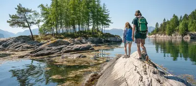 a man and a woman standing on a rock in the water at Waerholmen in Lavik