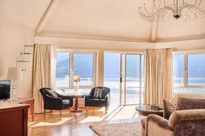 a living room with chairs and a table and windows at Hotel Ullensvang in Lofthus