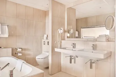 a bathroom with a sink and a toilet and a mirror at Hotel Ullensvang in Lofthus