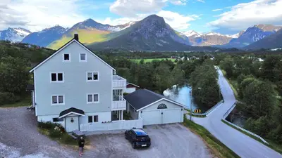 a large white house with a car parked in front of it at Apartment Dreamvalley in Isfjorden