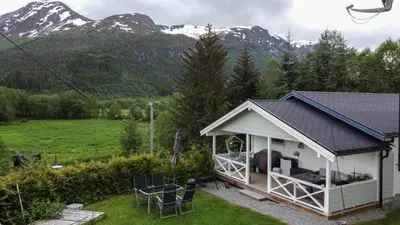 a cottage with a table and chairs and mountains in the background at Apartment Dreamvalley in Isfjorden