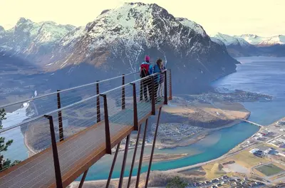 two people standing on a wooden walkway over a mountain at Apartment Dreamvalley in Isfjorden