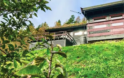 a house on a grassy hill next to a building at Gorgeous Home In Norheimsund With Wifi in Norheimsund
