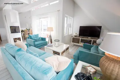 a living room with blue couches and a tv at Kalvåg Holidayapartment in Kalvåg