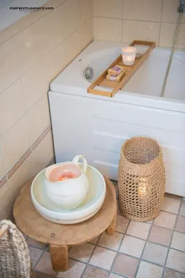 a bathroom with a bath tub and a table with a cup of tea at Kalvåg Holidayapartment in Kalvåg