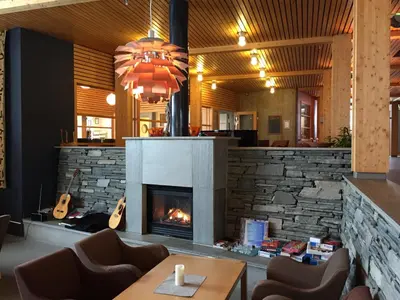 a fireplace in a restaurant with a table and chairs at Unicare Røros in Røros