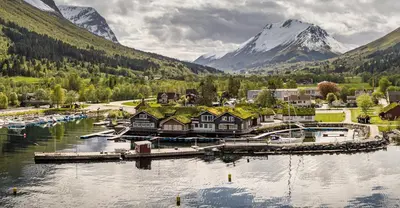 a village on a lake with mountains in the background at Sagafjord Hotel - by Classic Norway Hotels in Sæbø