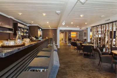 a restaurant with a bar and tables and chairs at Sagafjord Hotel - by Classic Norway Hotels in Sæbø