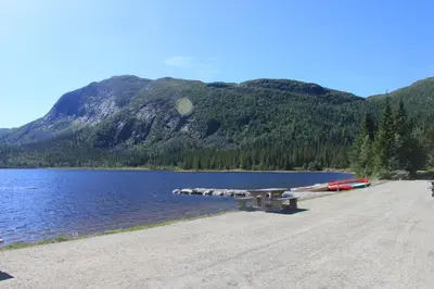 a picnic table on a beach next to a lake at Haglebu Feriesenter in Eggedal