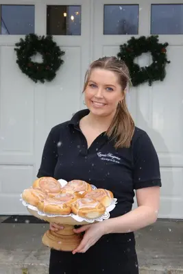 a woman holding a tray of donuts on a plate at Eggedal Borgerstue in Eggedal