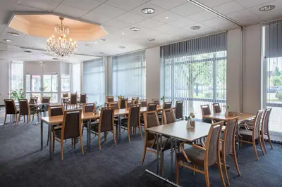 a dining room with tables and chairs and windows at Scandic Hønefoss in Hønefoss