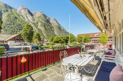 a balcony with tables and chairs with mountains in the background at Vik Pensjonat in Eidfjord