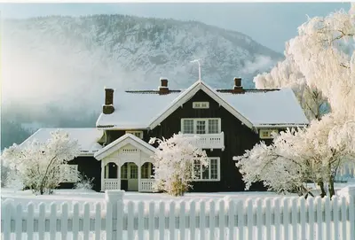 a black house with a snow covered roof with a fence at Hagaled Gjestegård in Nesbyen