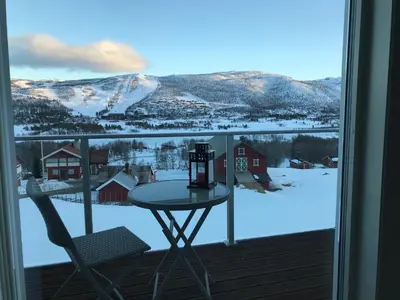 a table and a chair on a balcony with snow at Geilo Superior leilighet in Geilo