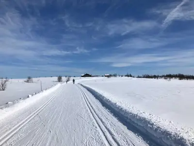 a snow covered road with a person walking down it at Geilo Superior leilighet in Geilo